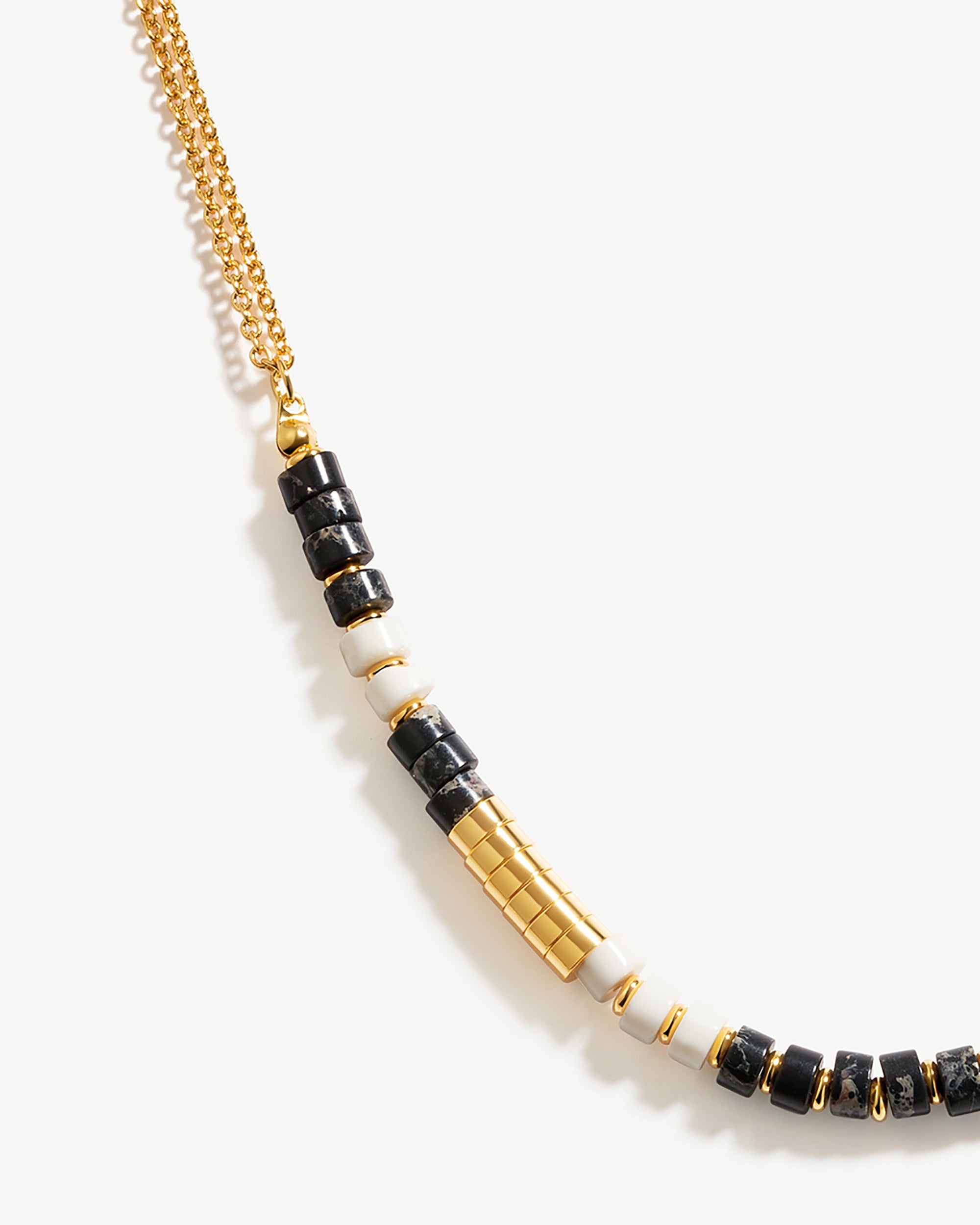 a black and white beaded necklace on a gold chain