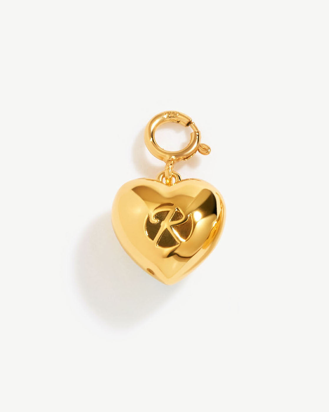 a gold heart shaped charm with a cross on it