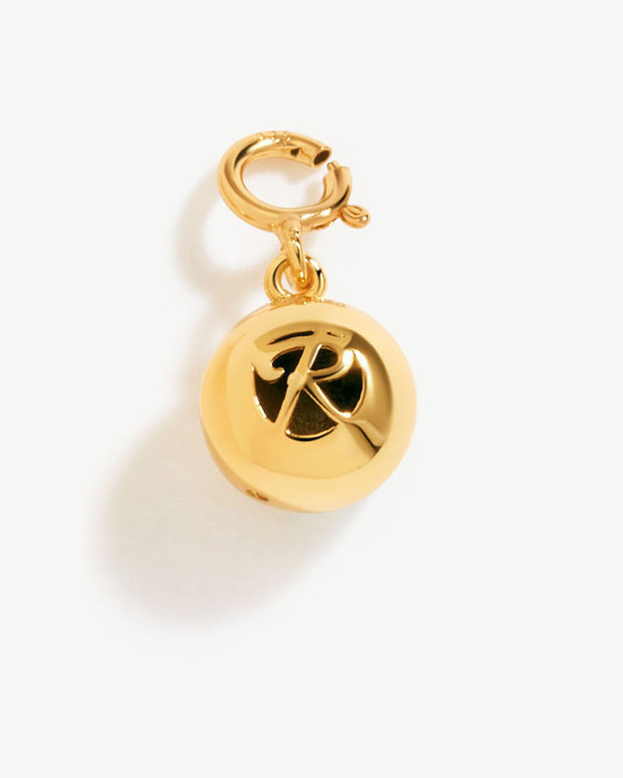 a gold charm with a letter on it