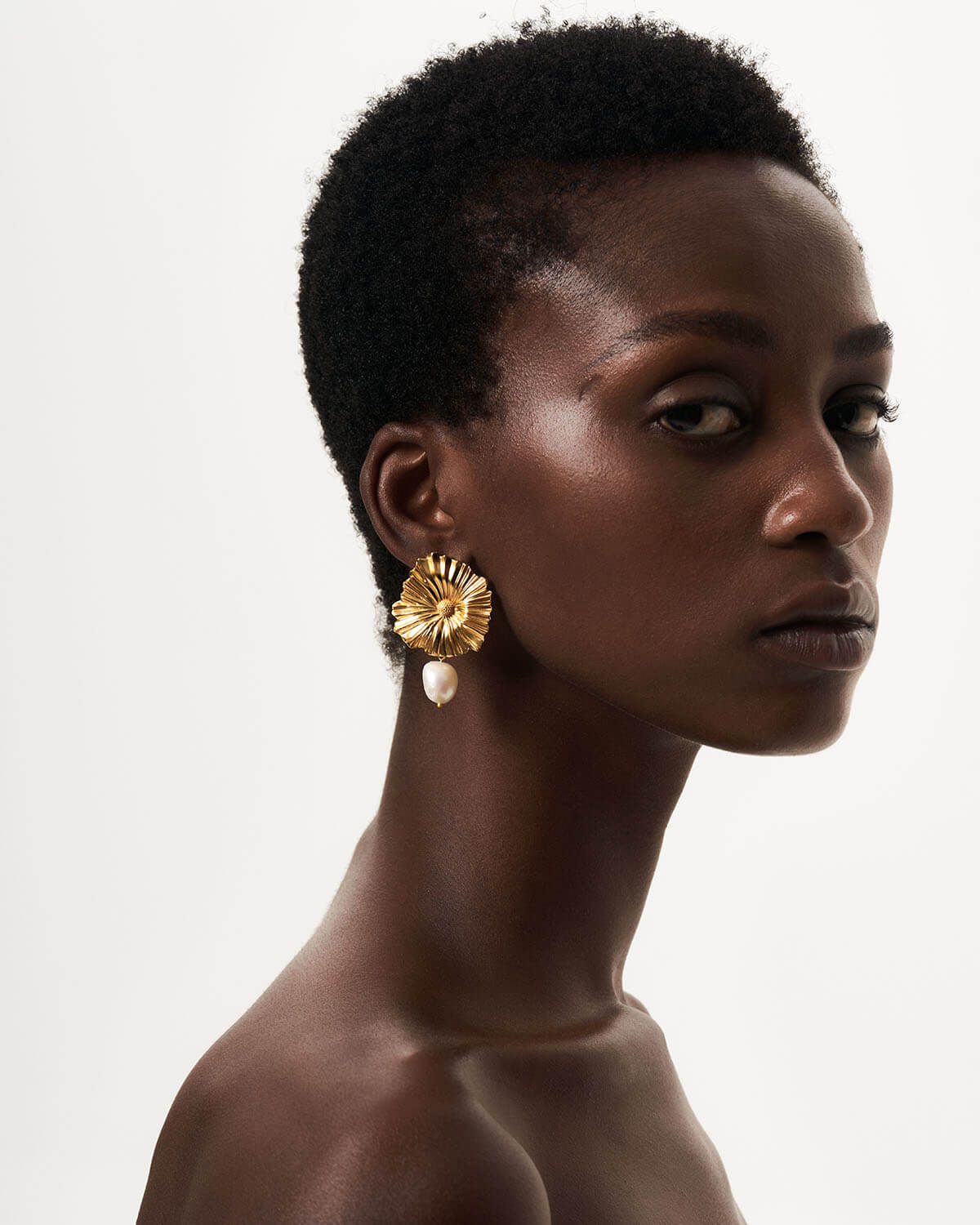 a woman wearing a pair of gold earrings