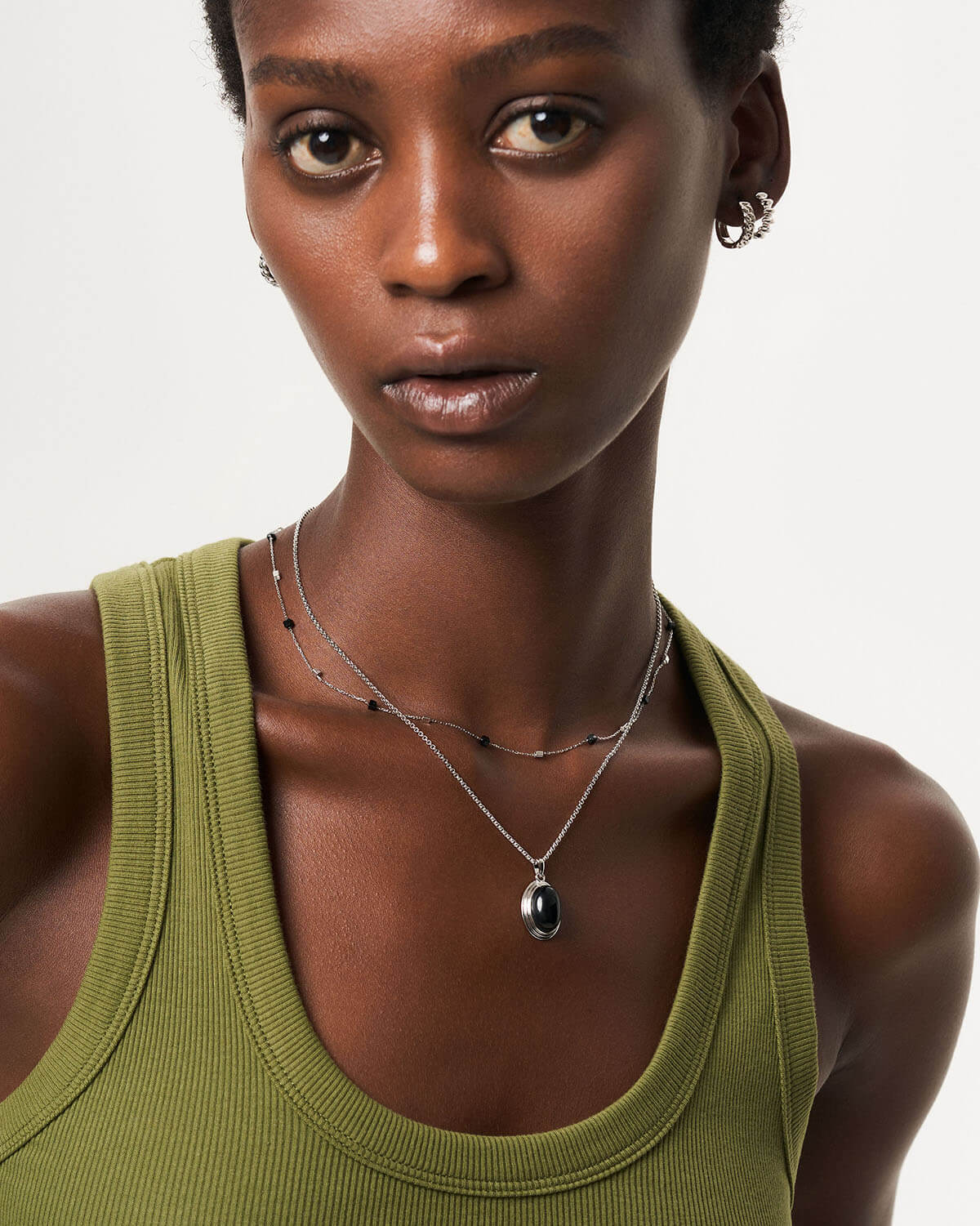 a woman wearing a green tank top and a necklace