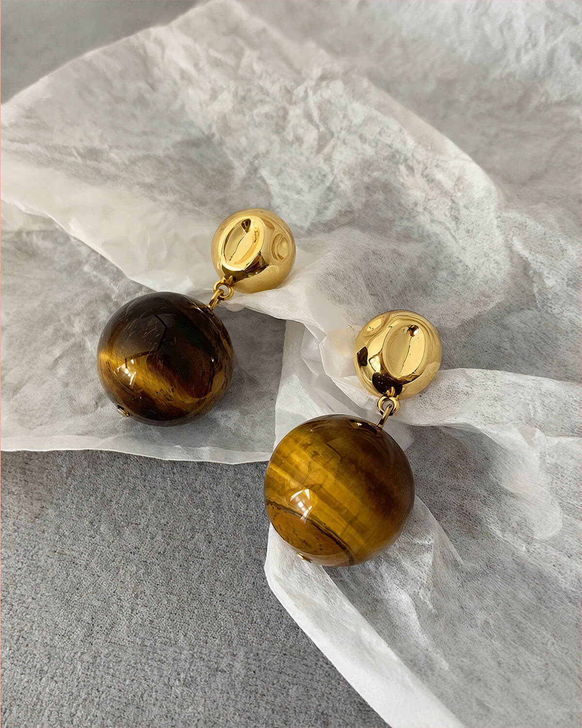 a pair of tiger's eye earrings sitting on top of a piece of paper