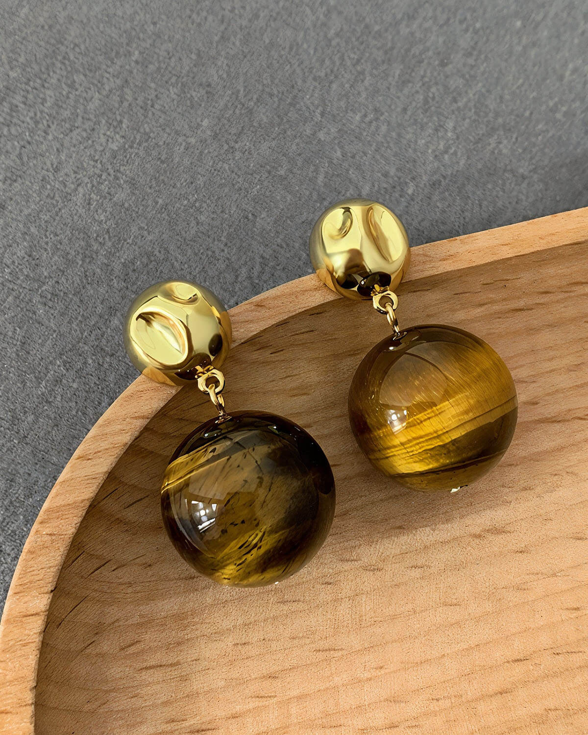 a pair of yellow and brown earrings on a wooden tray