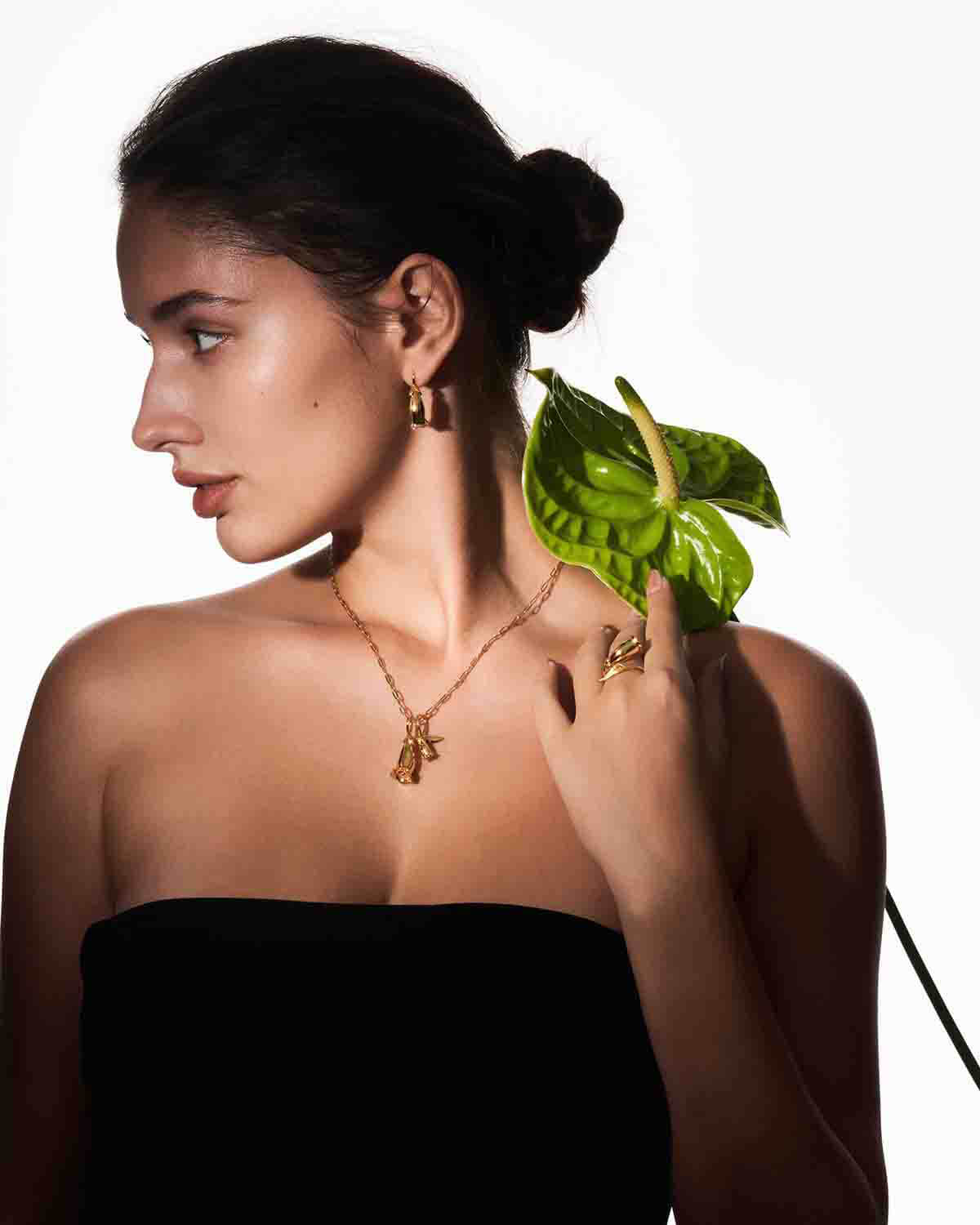 a woman in a black dress holding a green leaf