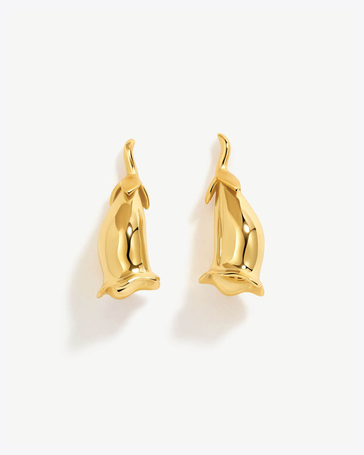 a pair of gold - plated dolphin earrings on a white background