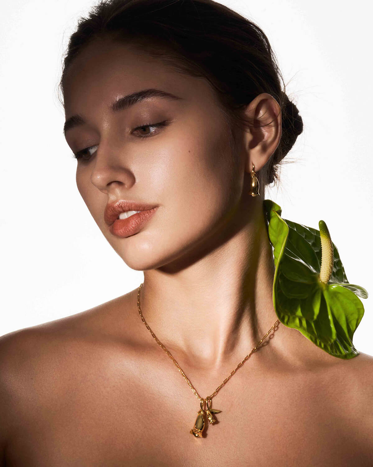 a woman with a leaf necklace on her neck