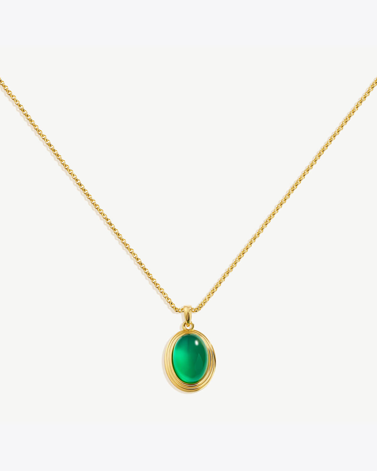 a gold necklace with a green stone on it