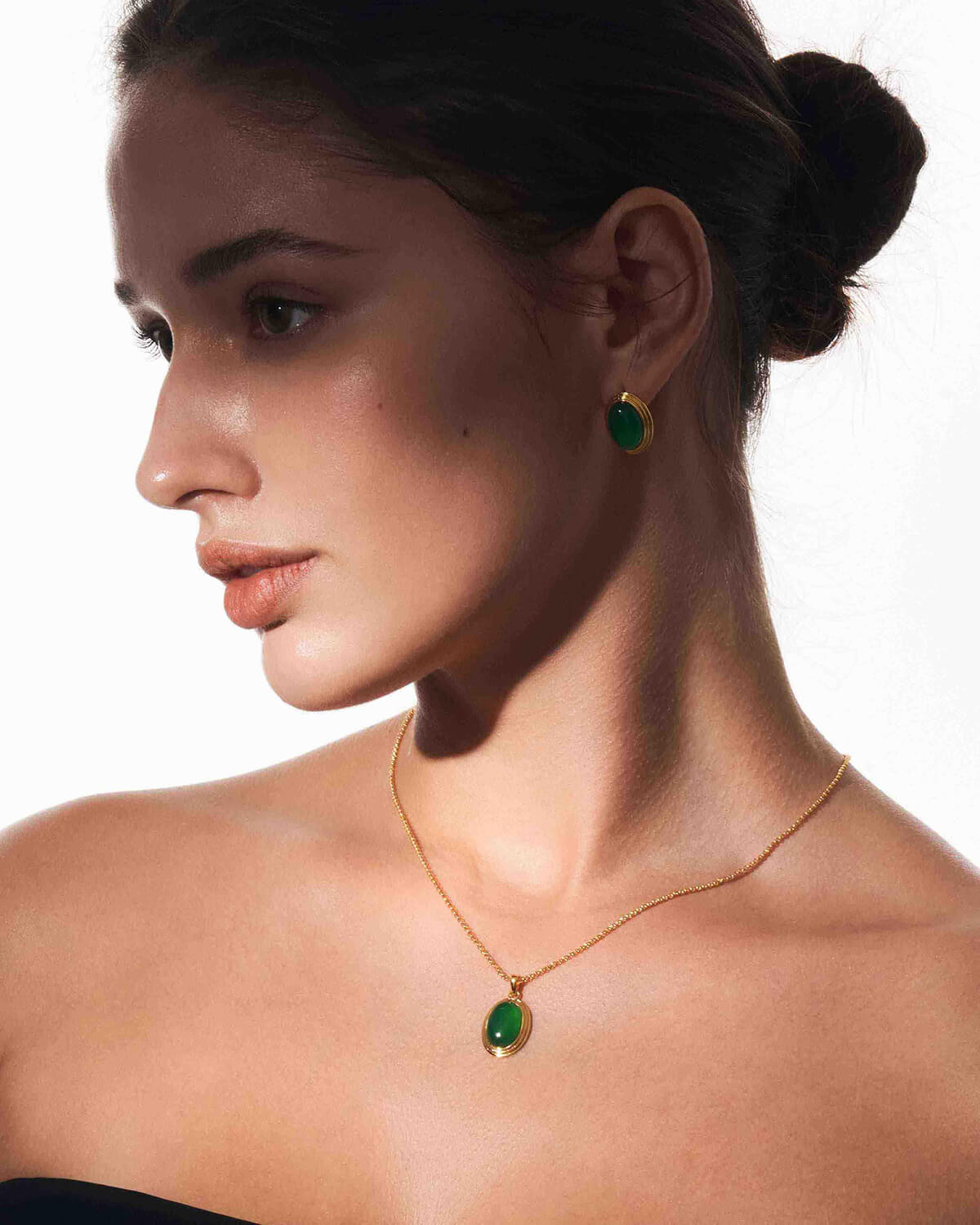 a woman wearing a green necklace and earrings