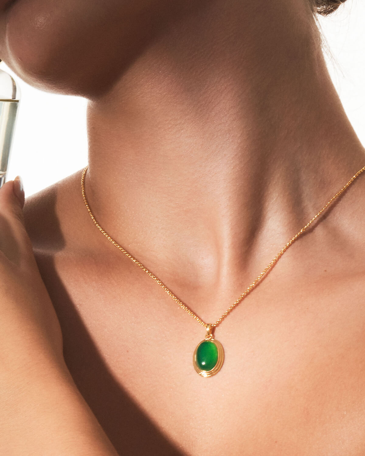 a woman wearing a necklace with a green stone