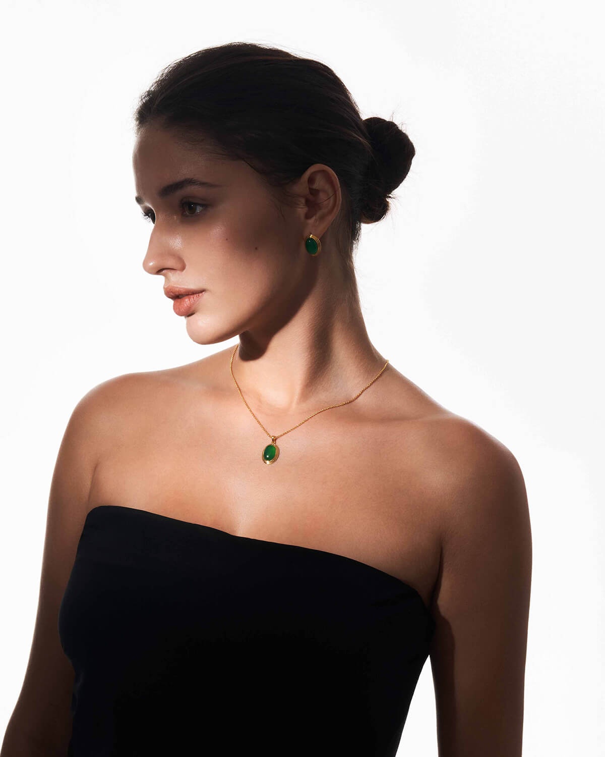 a woman in a black dress wearing a green necklace