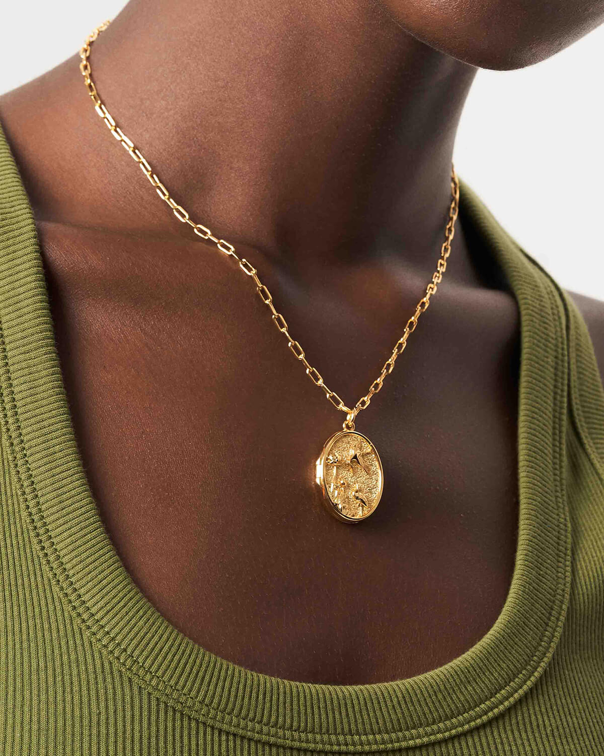 a woman wearing a gold necklace with a coin on it