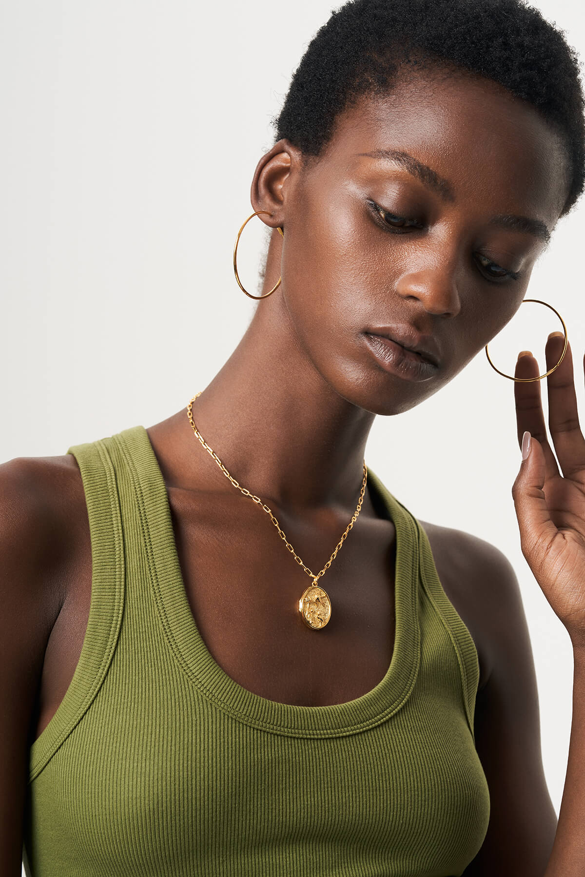 a woman wearing a green tank top and gold earrings