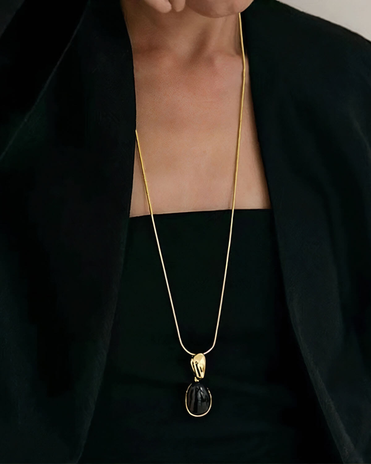 a woman wearing a black top and a gold necklace