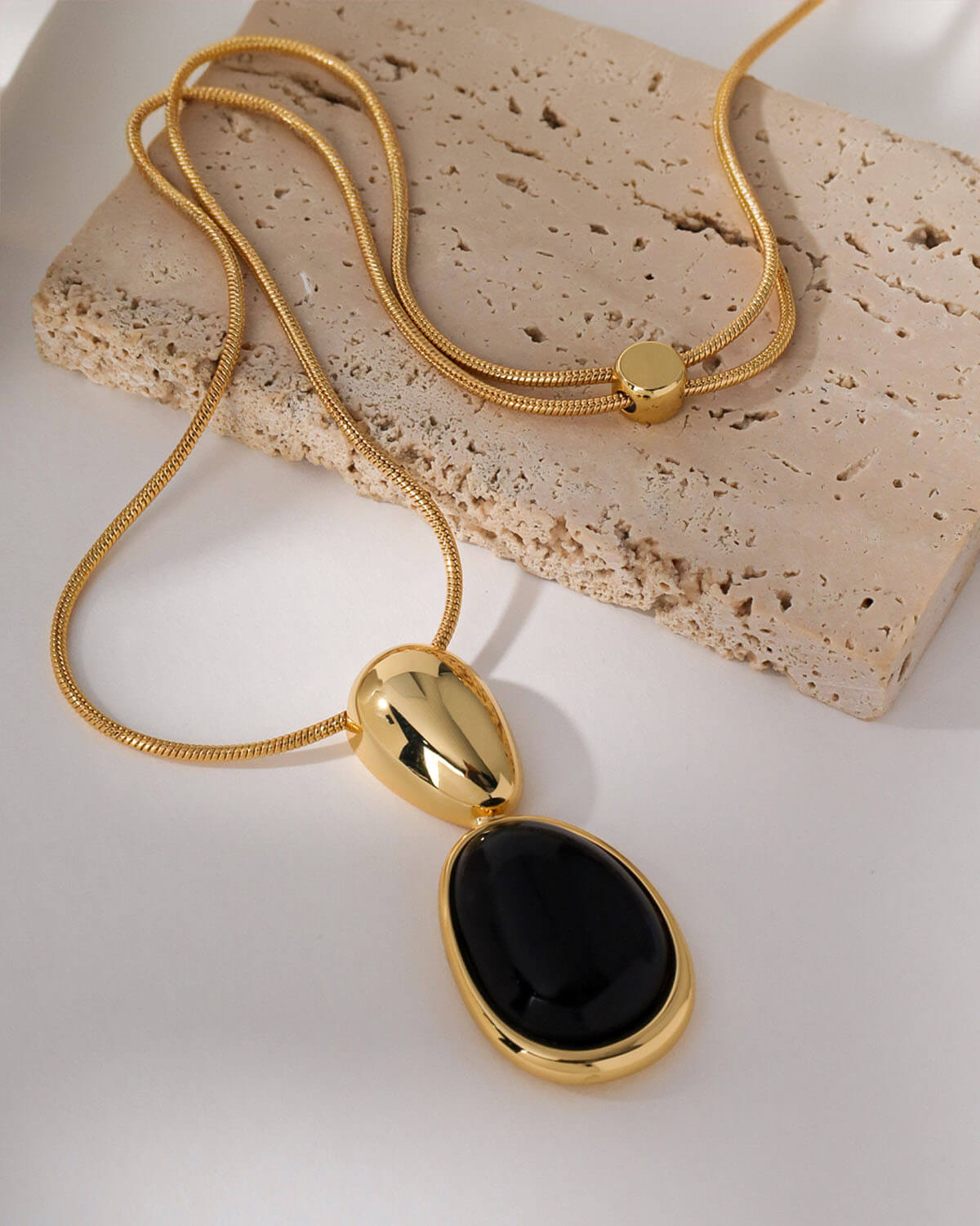 a gold necklace with a black stone on it