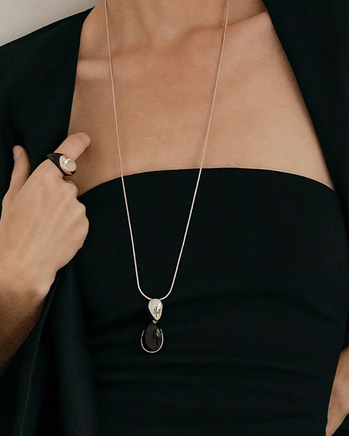 a woman wearing a black dress and a silver necklace