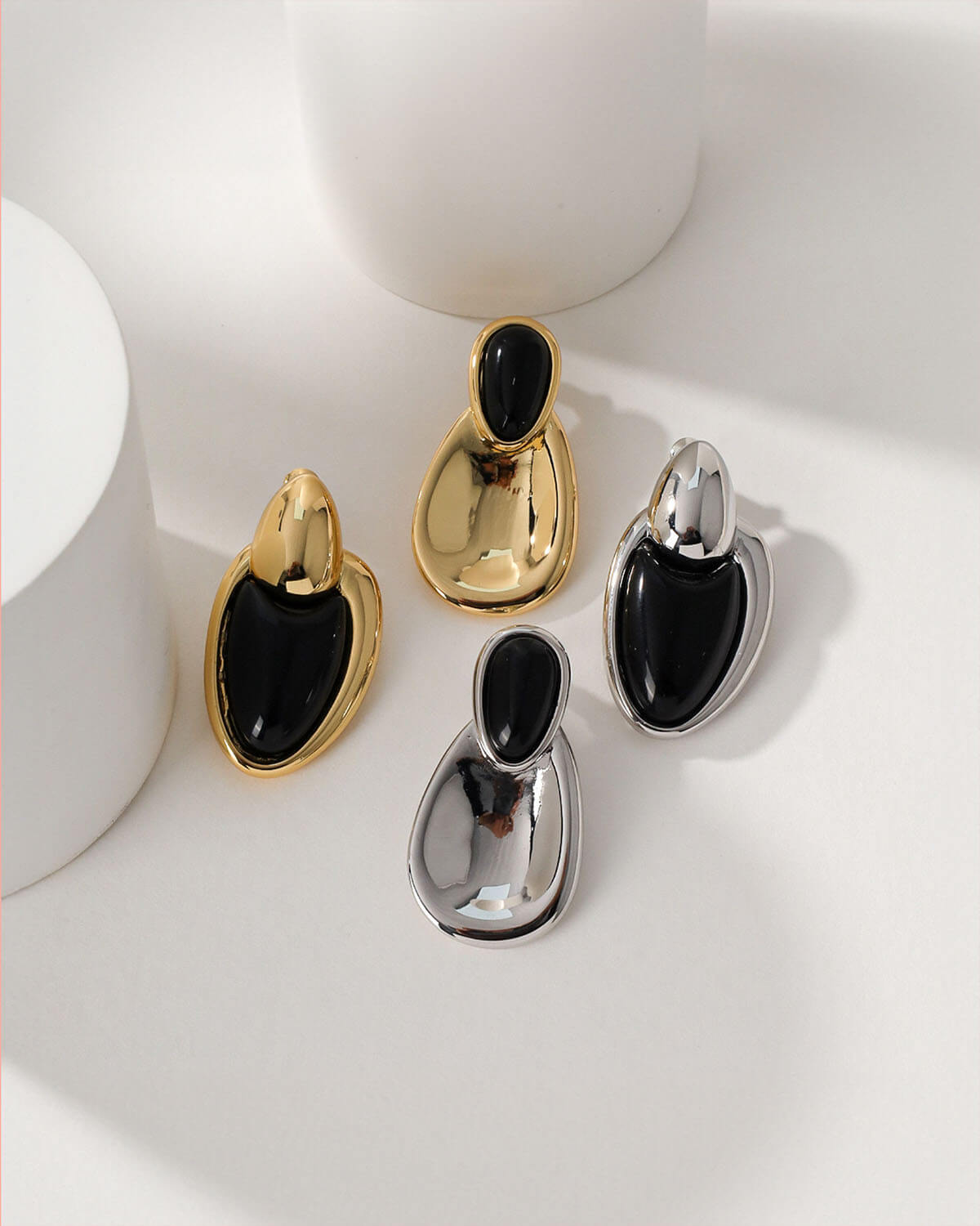 a group of black and gold earrings on a white surface