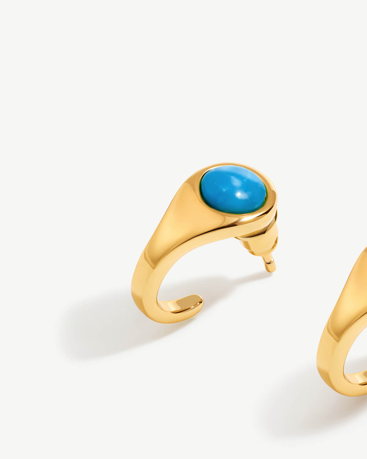 a pair of gold rings with a turquoise stone