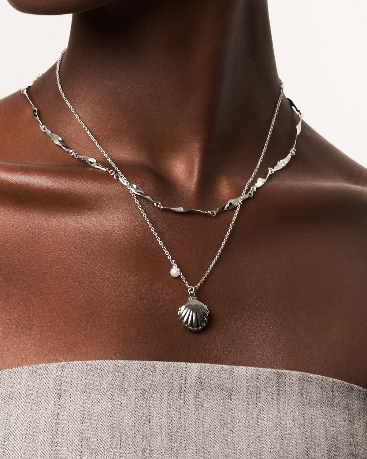 a woman wearing a necklace with a shell on it