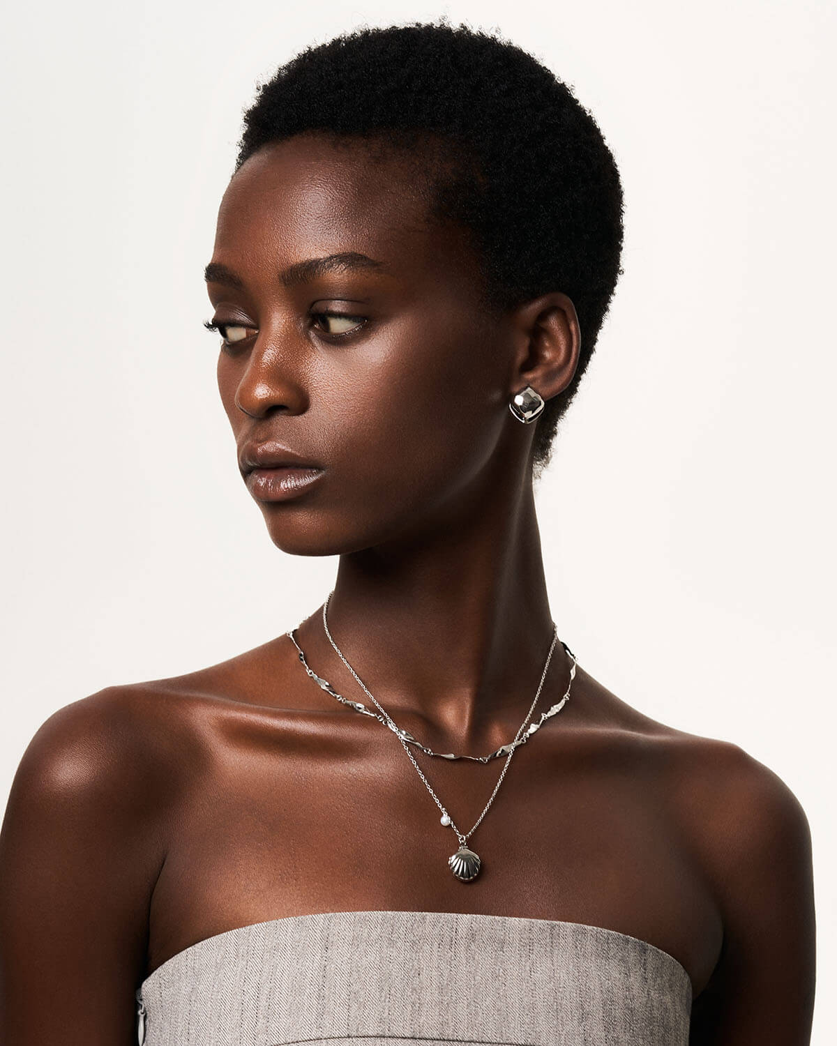 a woman wearing a necklace and earrings