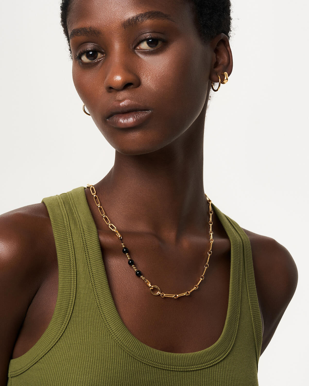 a woman wearing a green tank top and a gold chain necklace