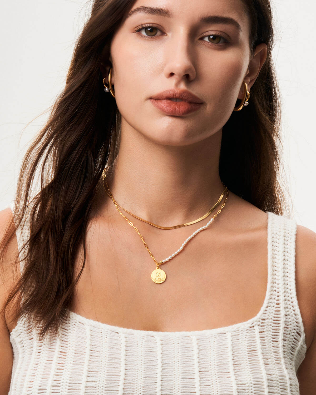 a woman wearing a white top and a gold necklace