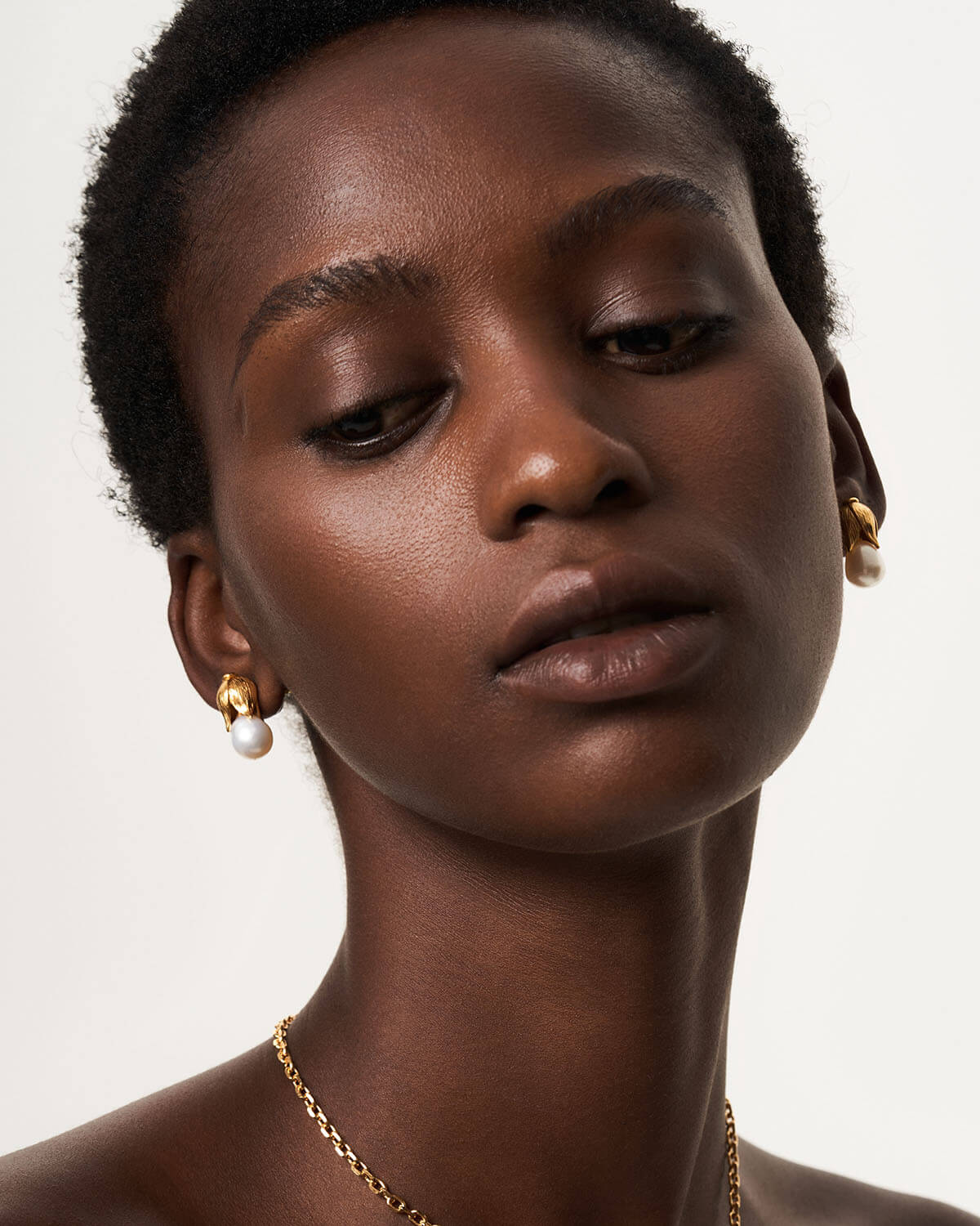 a close up of a woman wearing a necklace and earrings