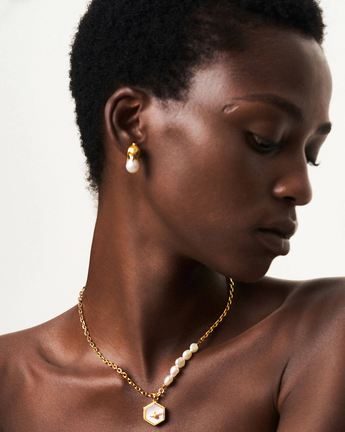 a woman wearing a necklace with pearls on it