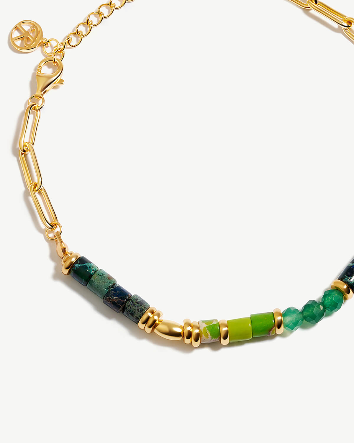 a gold bracelet with green and yellow beads