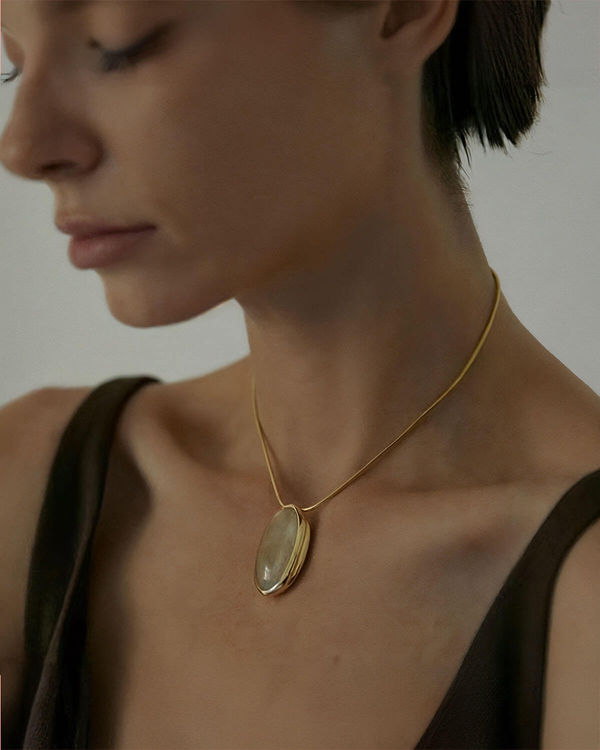 a woman wearing a necklace with a shell on it