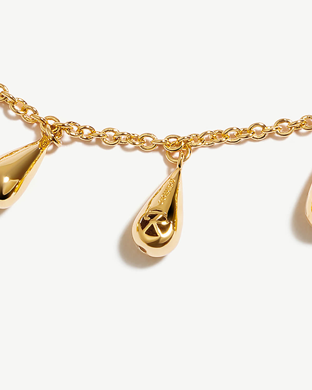 a close up of a gold necklace with three charms