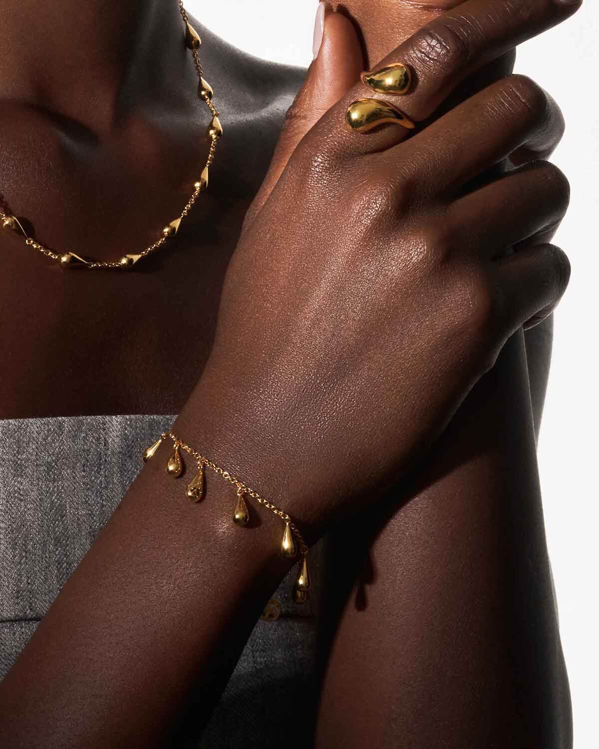 a woman wearing a gold bracelet and ring