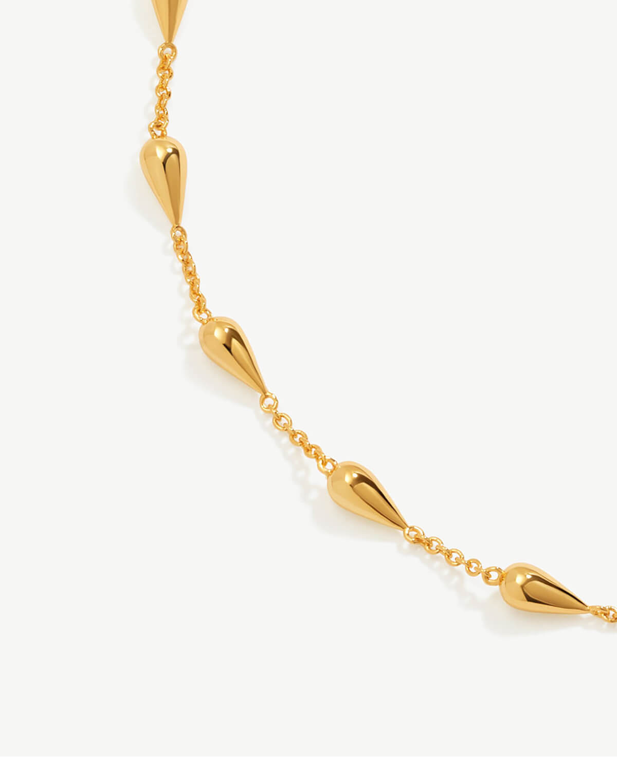 a gold necklace with spikes on a white background