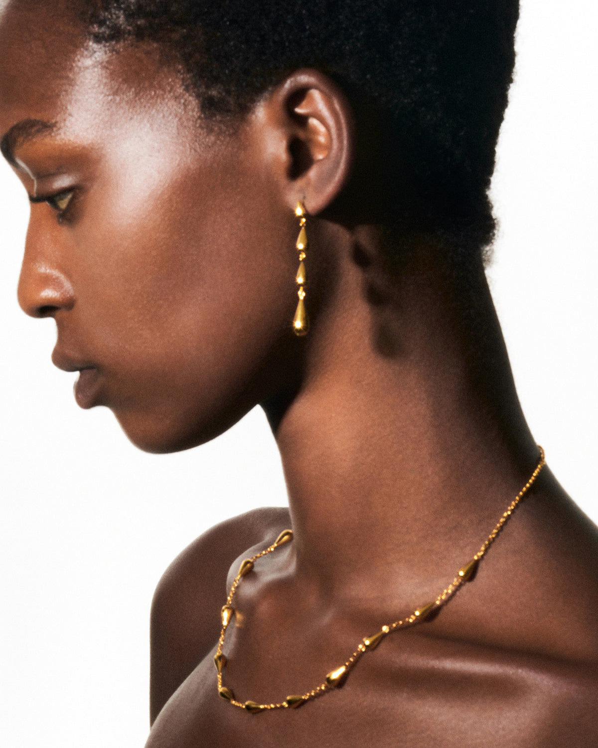 a woman wearing a gold necklace and earrings