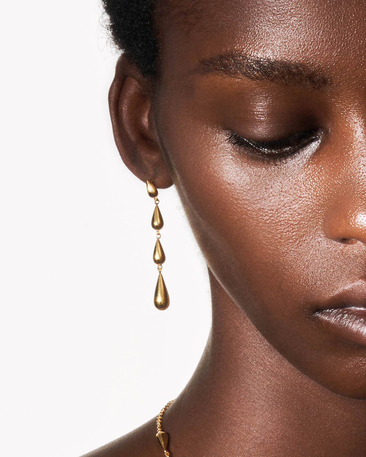 a close up of a person wearing a necklace and earrings