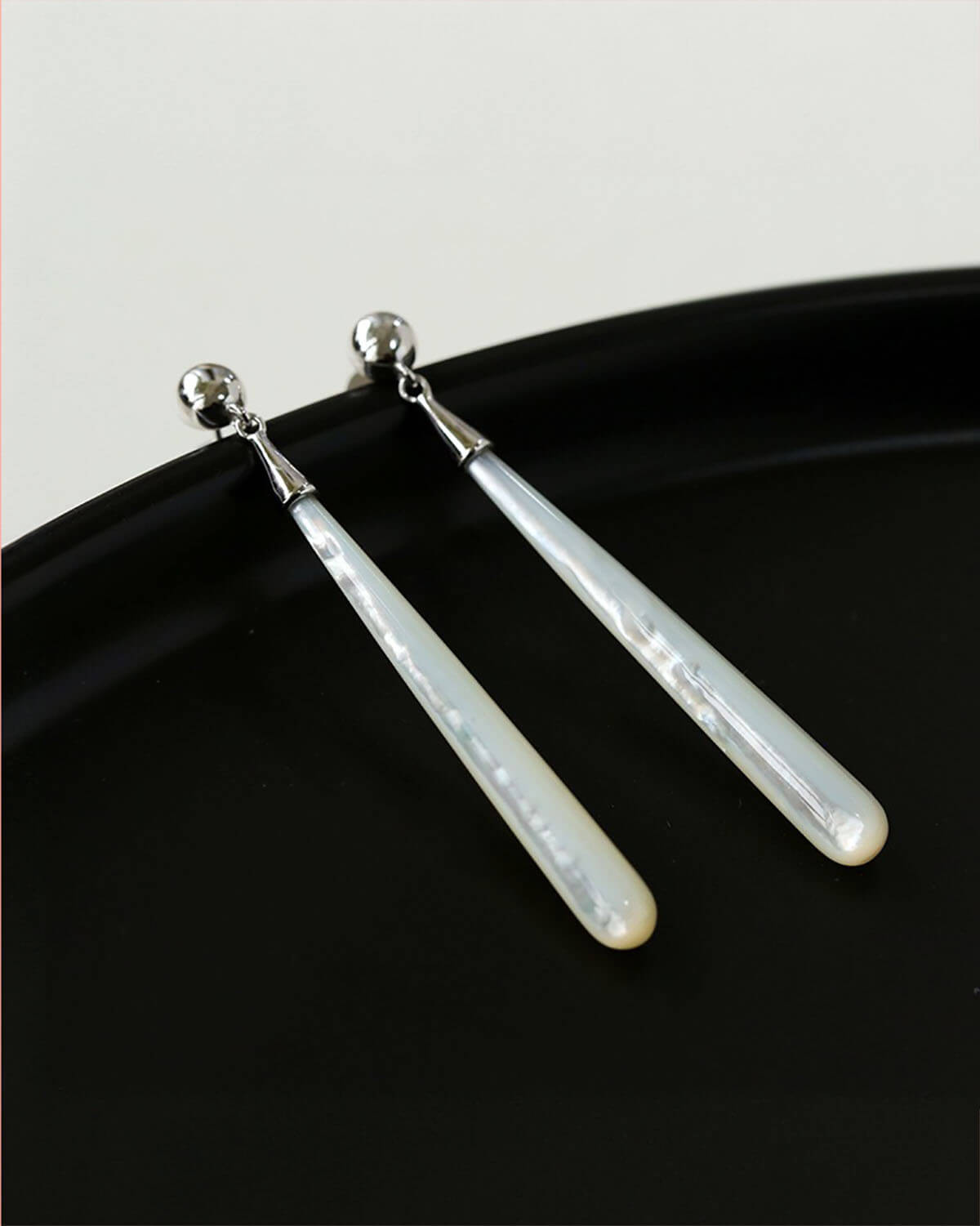 a pair of silver - plated earrings on a black plate