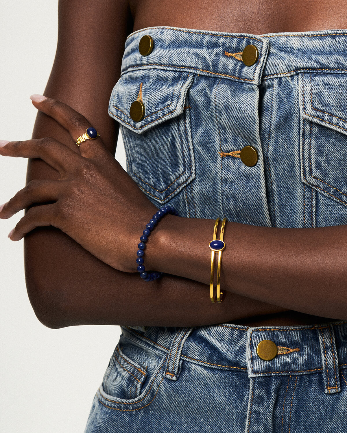 a woman wearing two bracelets and a denim dress