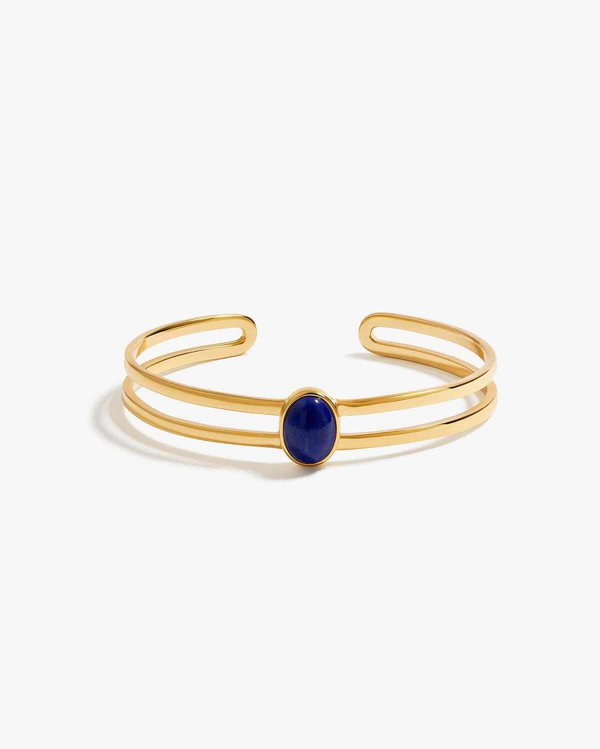 a gold cuff bracelet with a blue stone