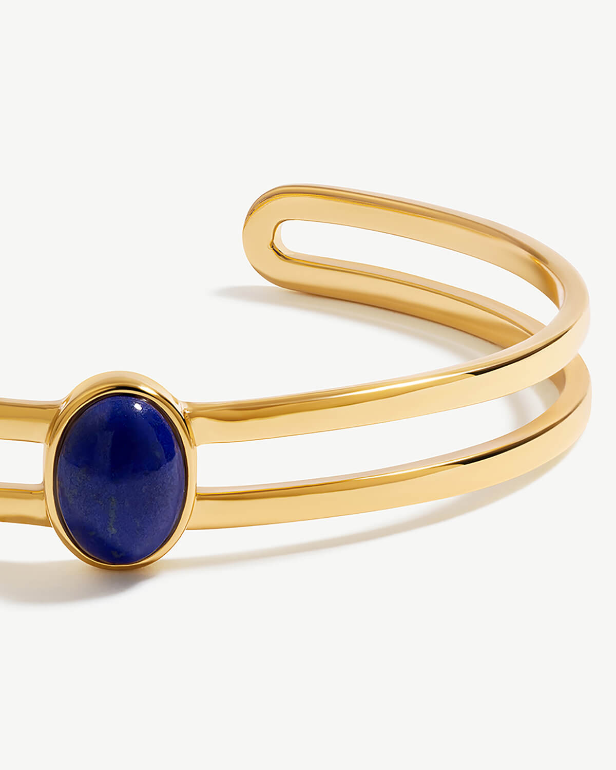 a gold cuff bracelet with a blue stone