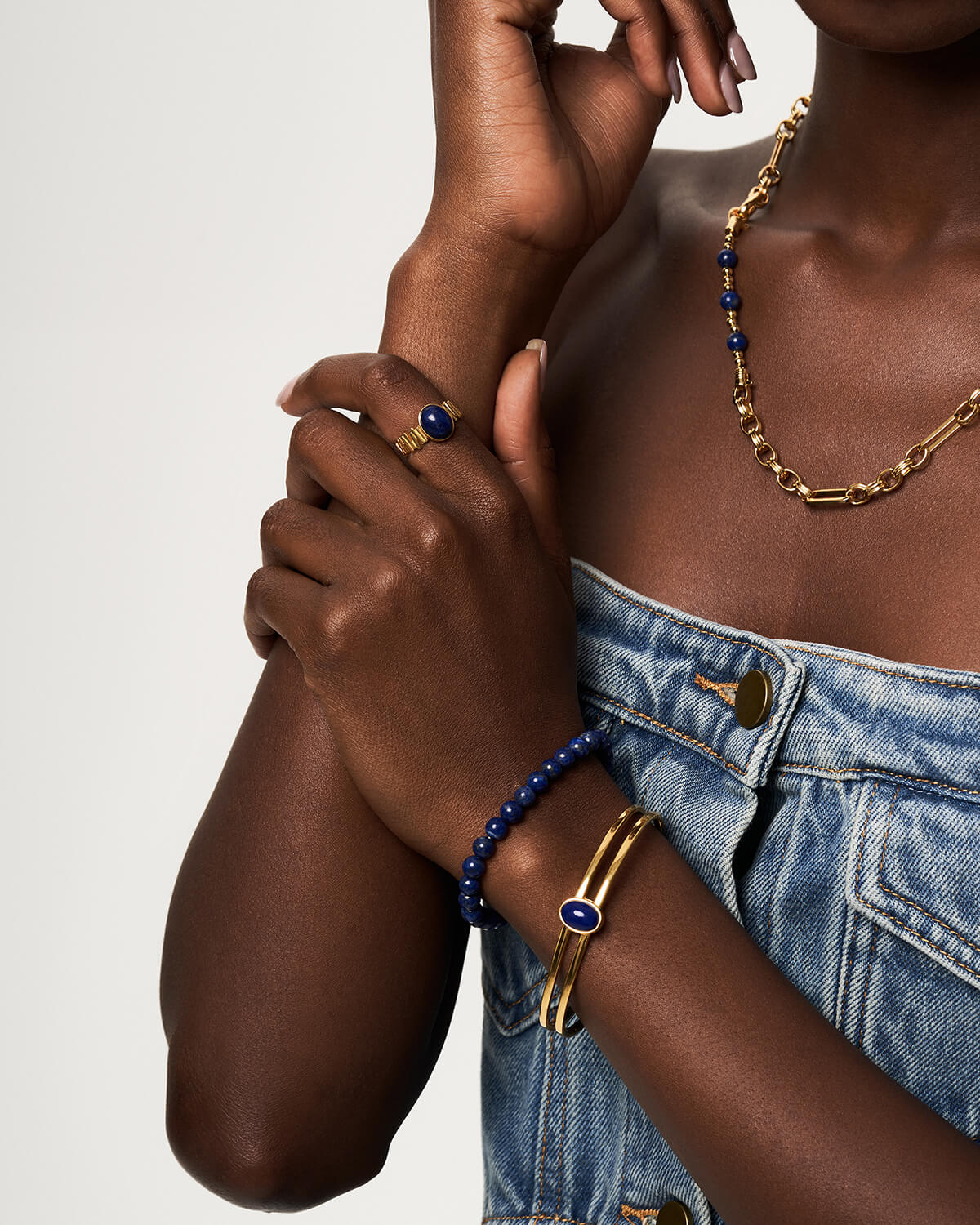 a woman wearing a denim dress and a gold bracelet