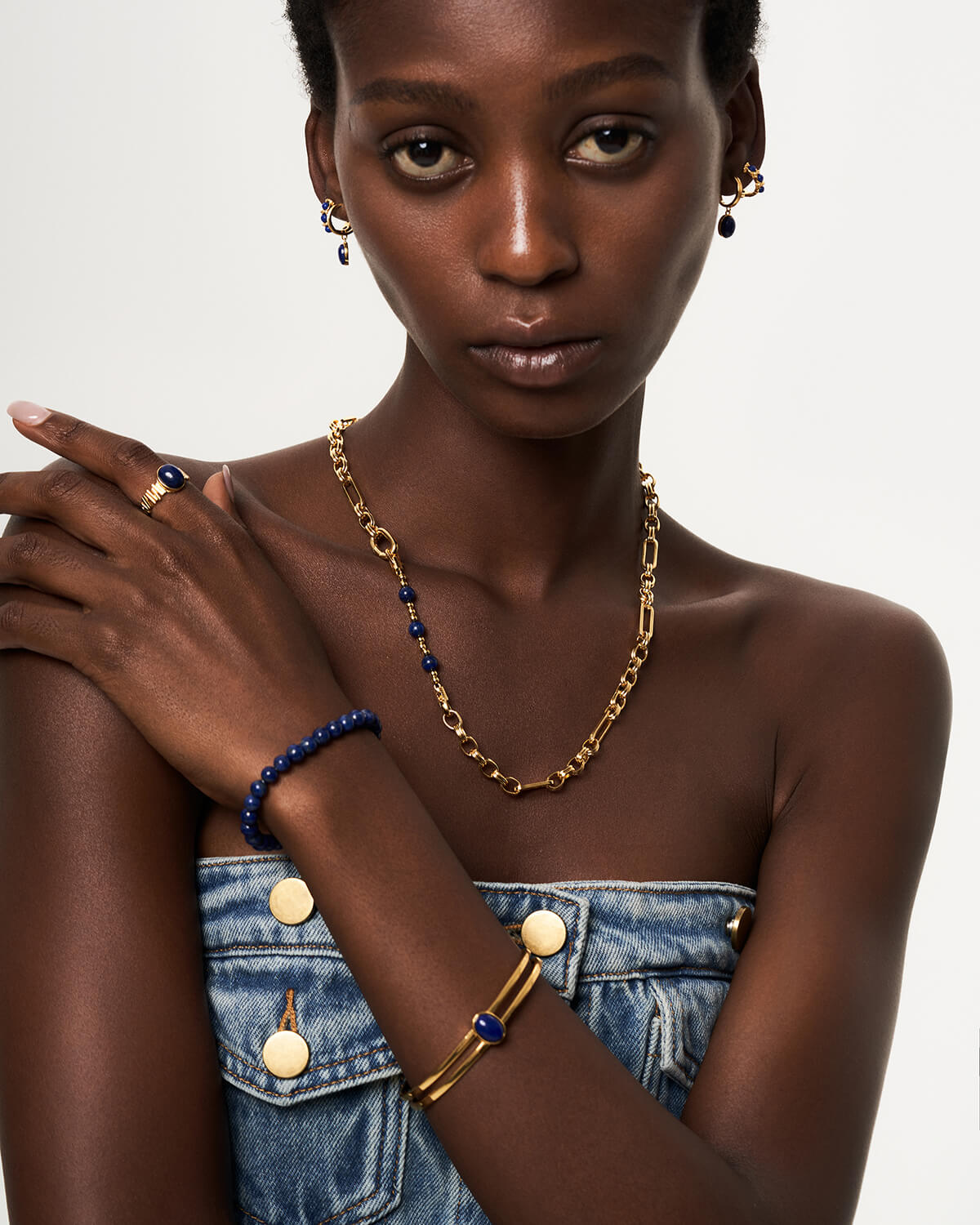 a woman wearing a denim dress and a gold chain necklace