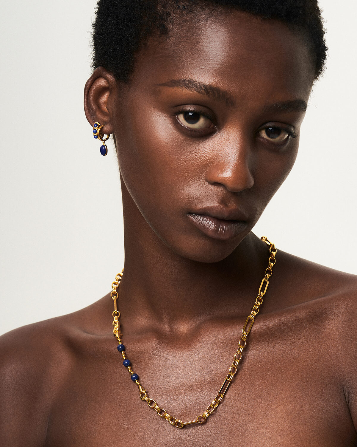 a woman wearing a gold necklace and earrings