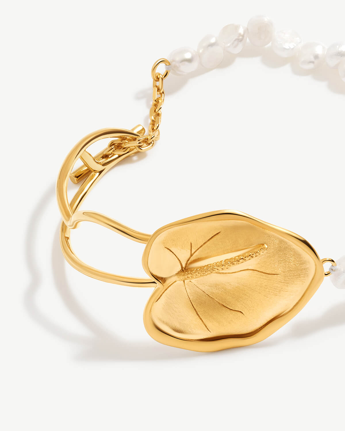 a close up of a bracelet with a leaf on it