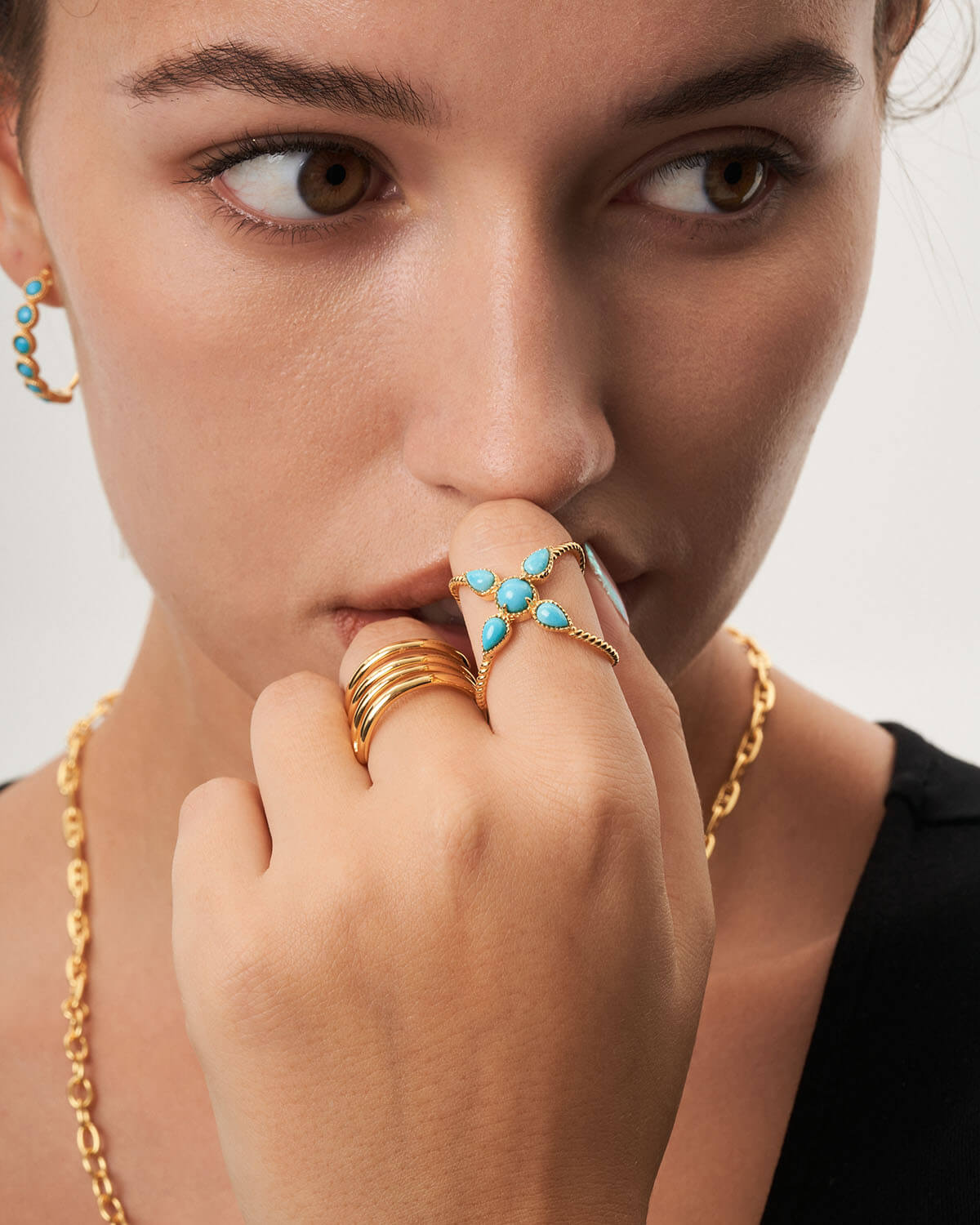 a woman wearing a gold ring with turquoise stones