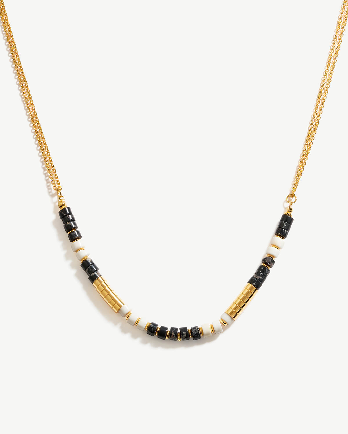 a black and white beaded necklace on a gold chain