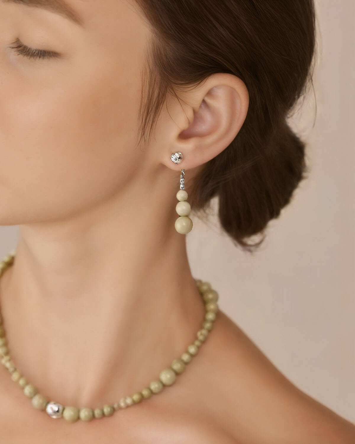 a woman wearing a green necklace and earrings