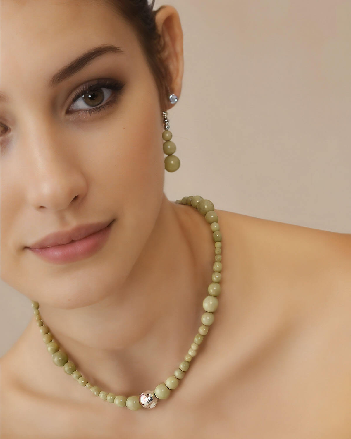 a woman wearing a green necklace and earrings