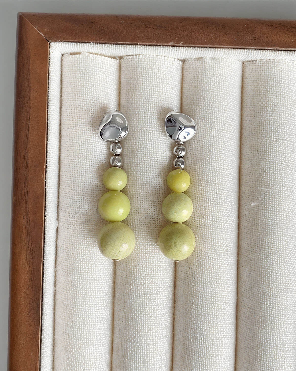 a pair of yellow and white earrings in a wooden frame