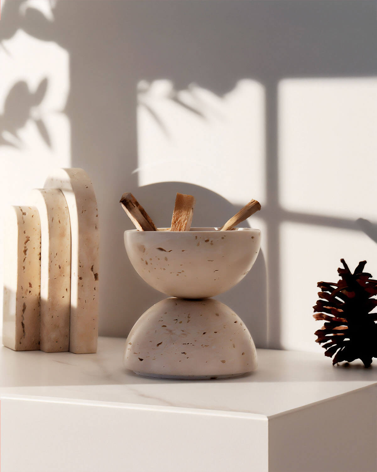 a white bowl sitting on top of a counter next to a pine cone