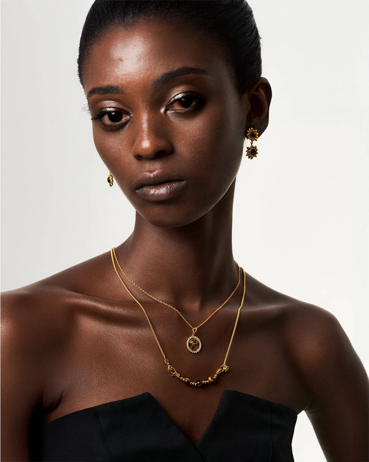 a woman in a black dress wearing a gold necklace