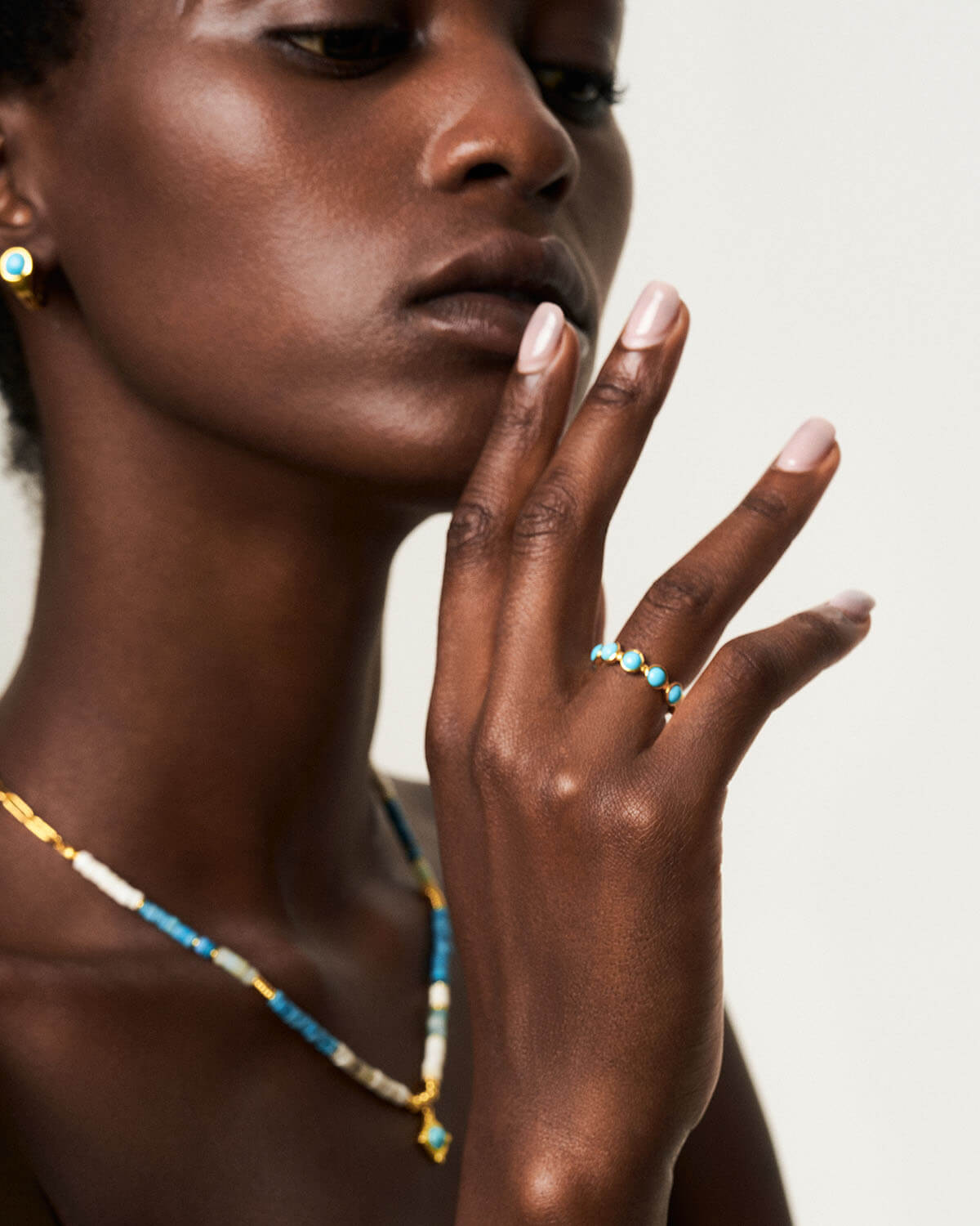 a woman with a necklace and ring on her hand